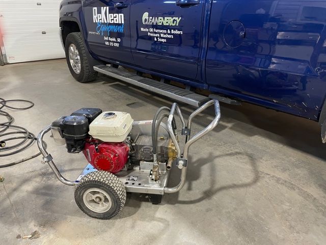A blue truck with a pressure washer attached to it