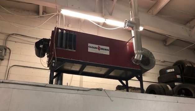 A red heater is hanging from the ceiling in a garage.