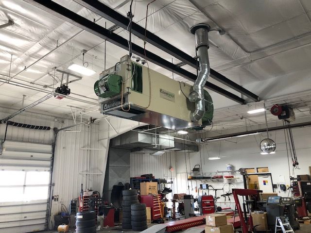 A large machine is hanging from the ceiling of a garage.