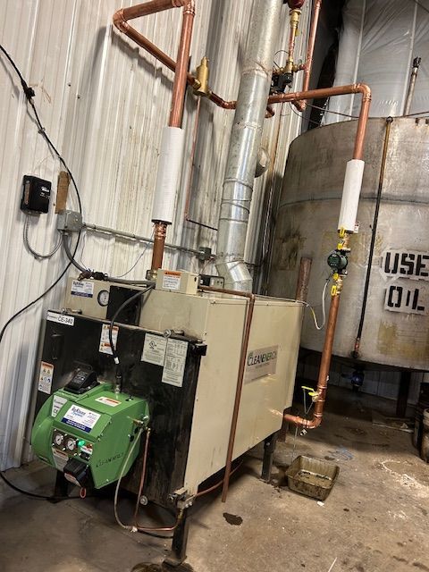 A boiler is sitting in a room next to a tank that says use oil.