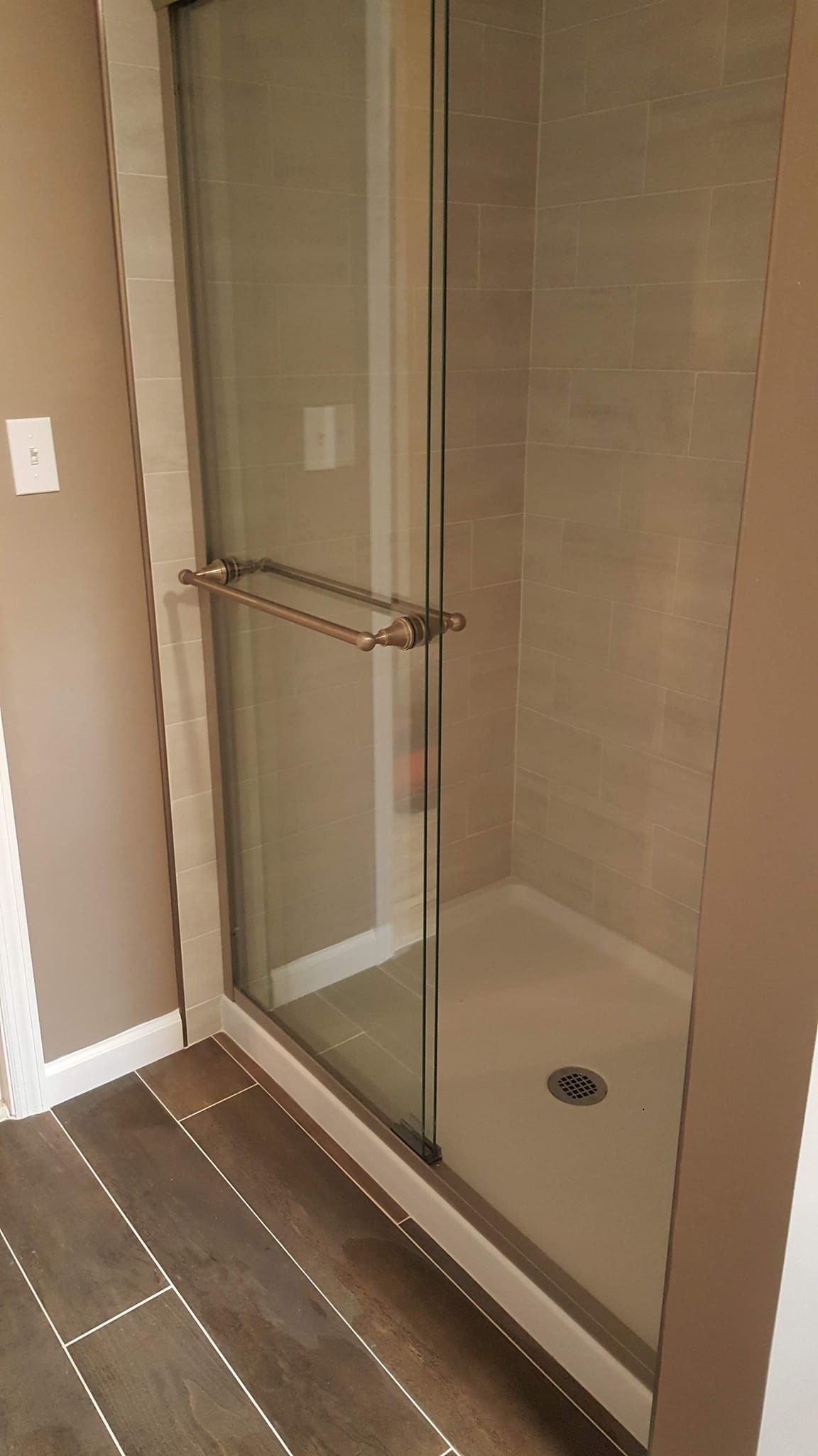 Shower stall with glass door and a silver handle