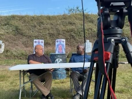 Close-up of a Canon DSLR camera recording two men in an interview setting. Close-up of a Canon DSLR camera recording two men in an interview setting.
