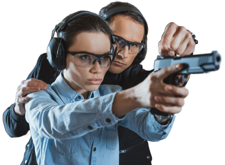 A woman in safety glasses and earmuffs is learning to shoot a handgun with the help of an instructor.