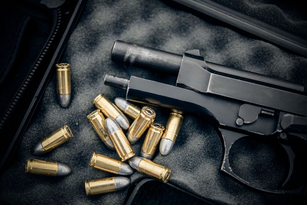 Black handgun and bullets on target sheets.