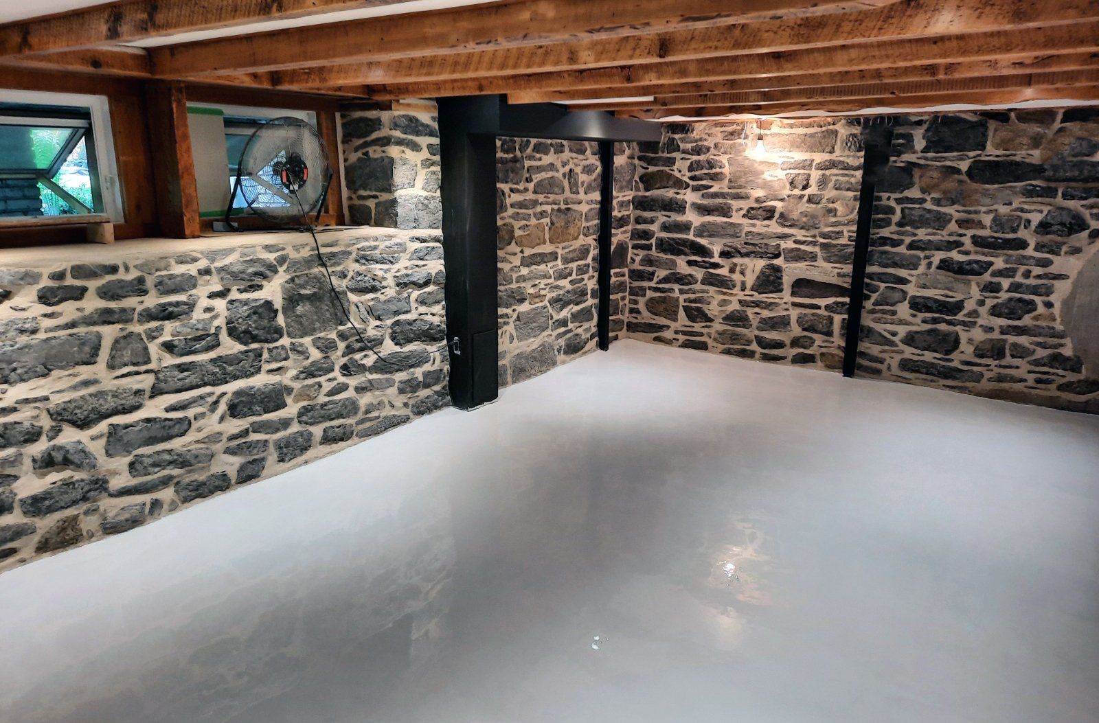 Un sous-sol vide avec un mur en pierre et un sol blanc.