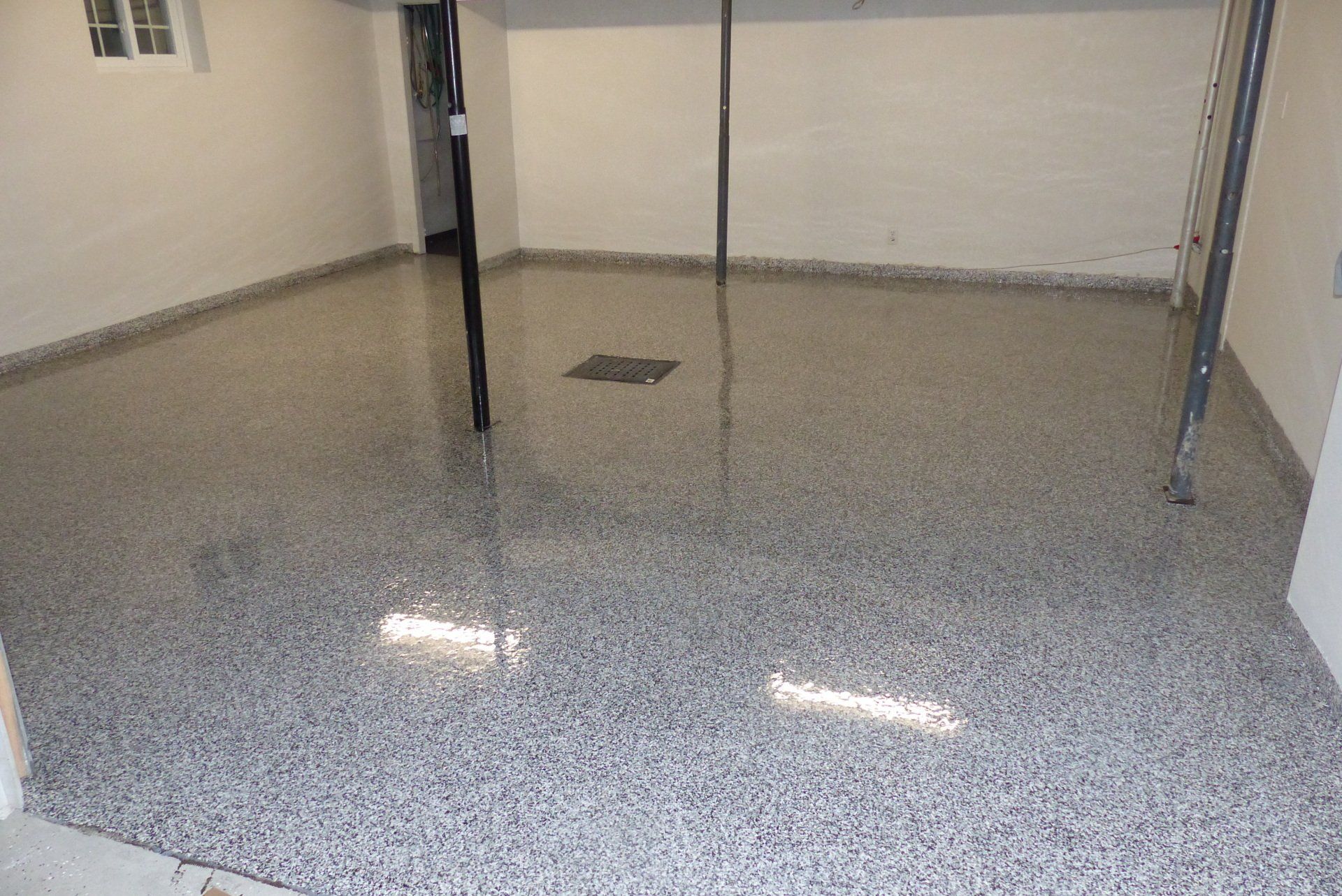 Un garage avec un sol gris et blanc et des murs blancs.