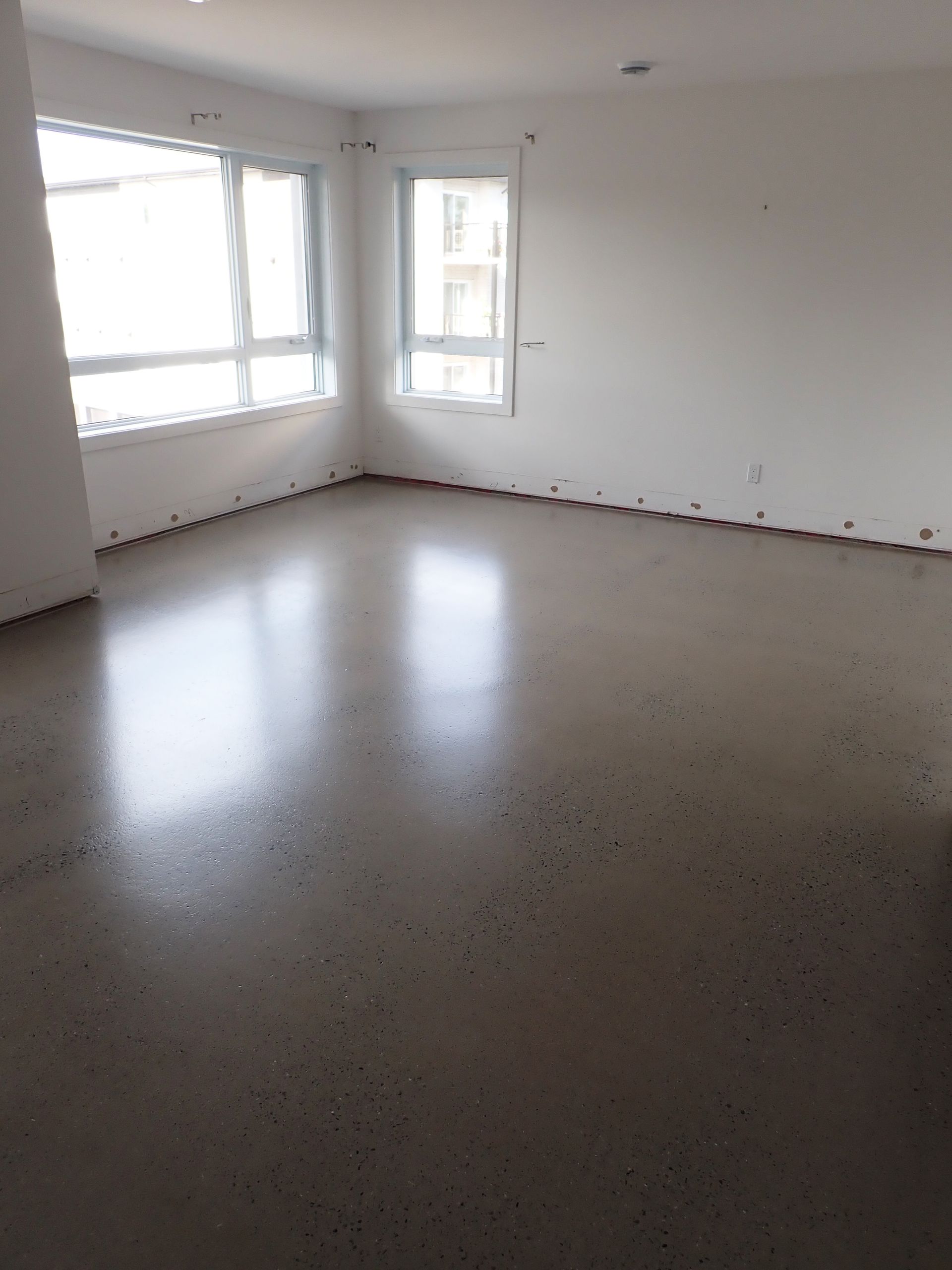 Une pièce vide avec un sol gris et des murs blancs