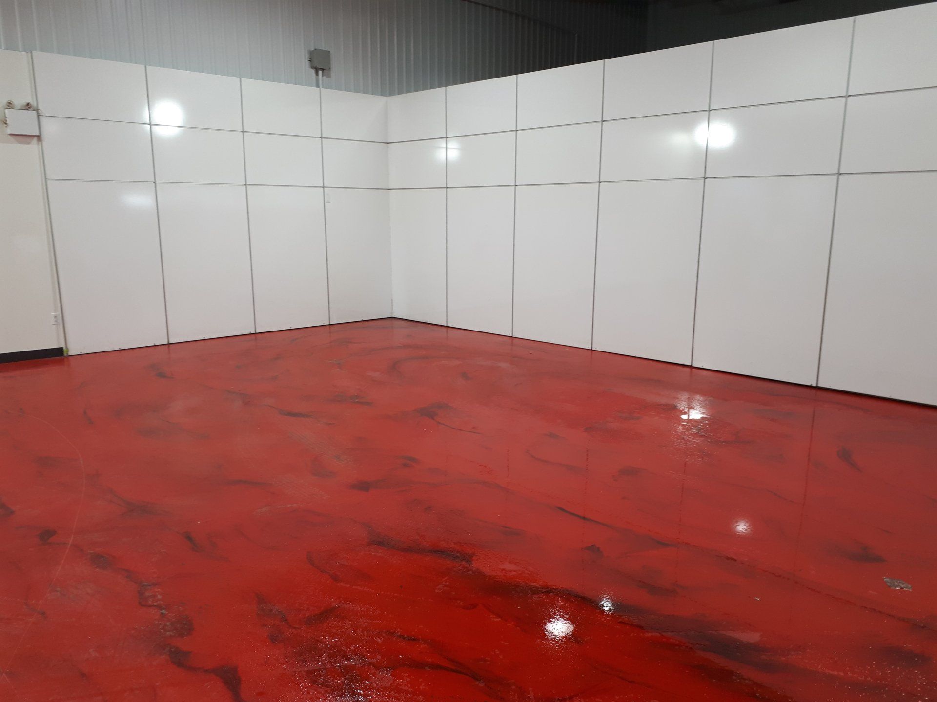 Une pièce avec un sol rouge et des murs blancs.