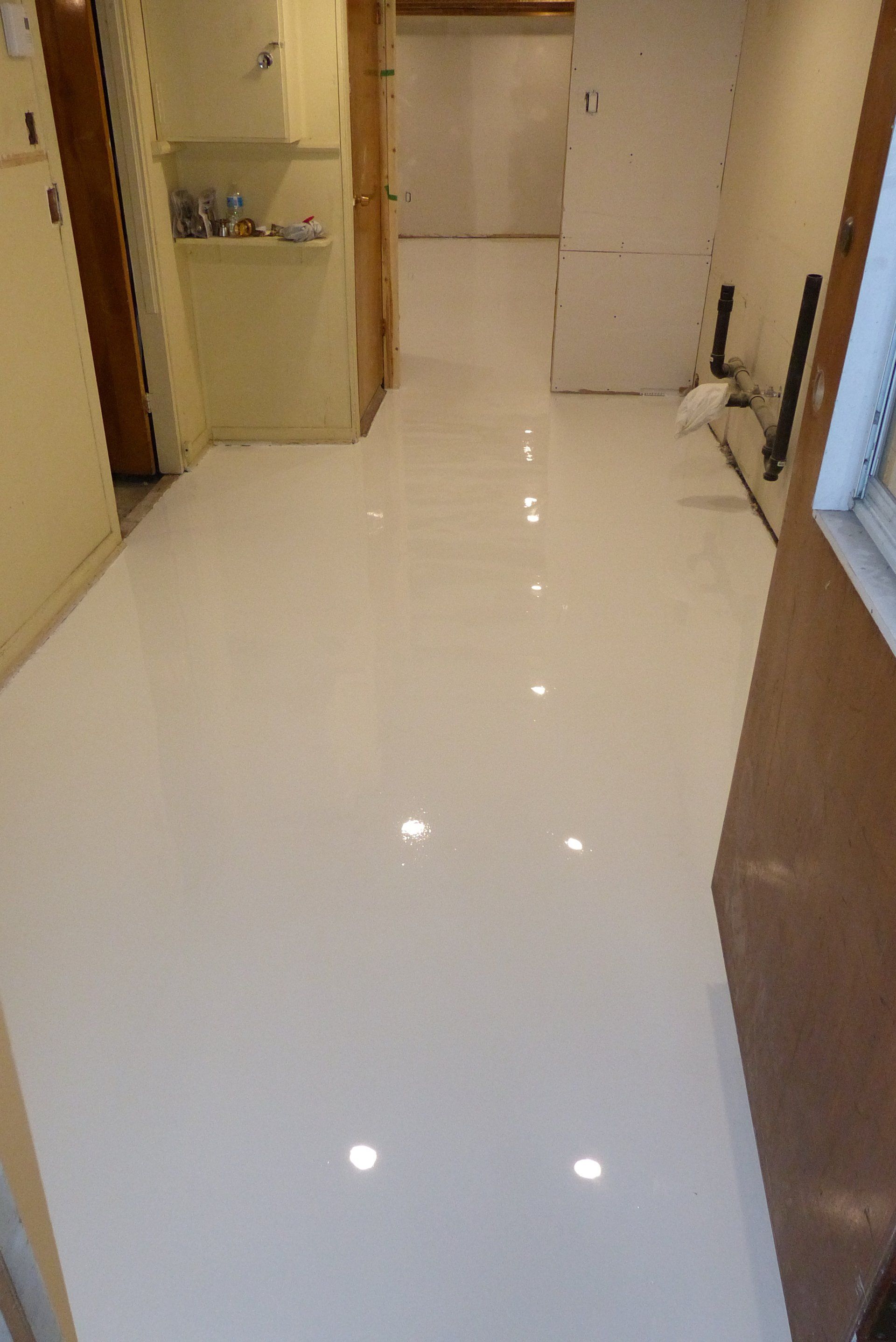 Un couloir avec un sol blanc et quelques lumières dessus.