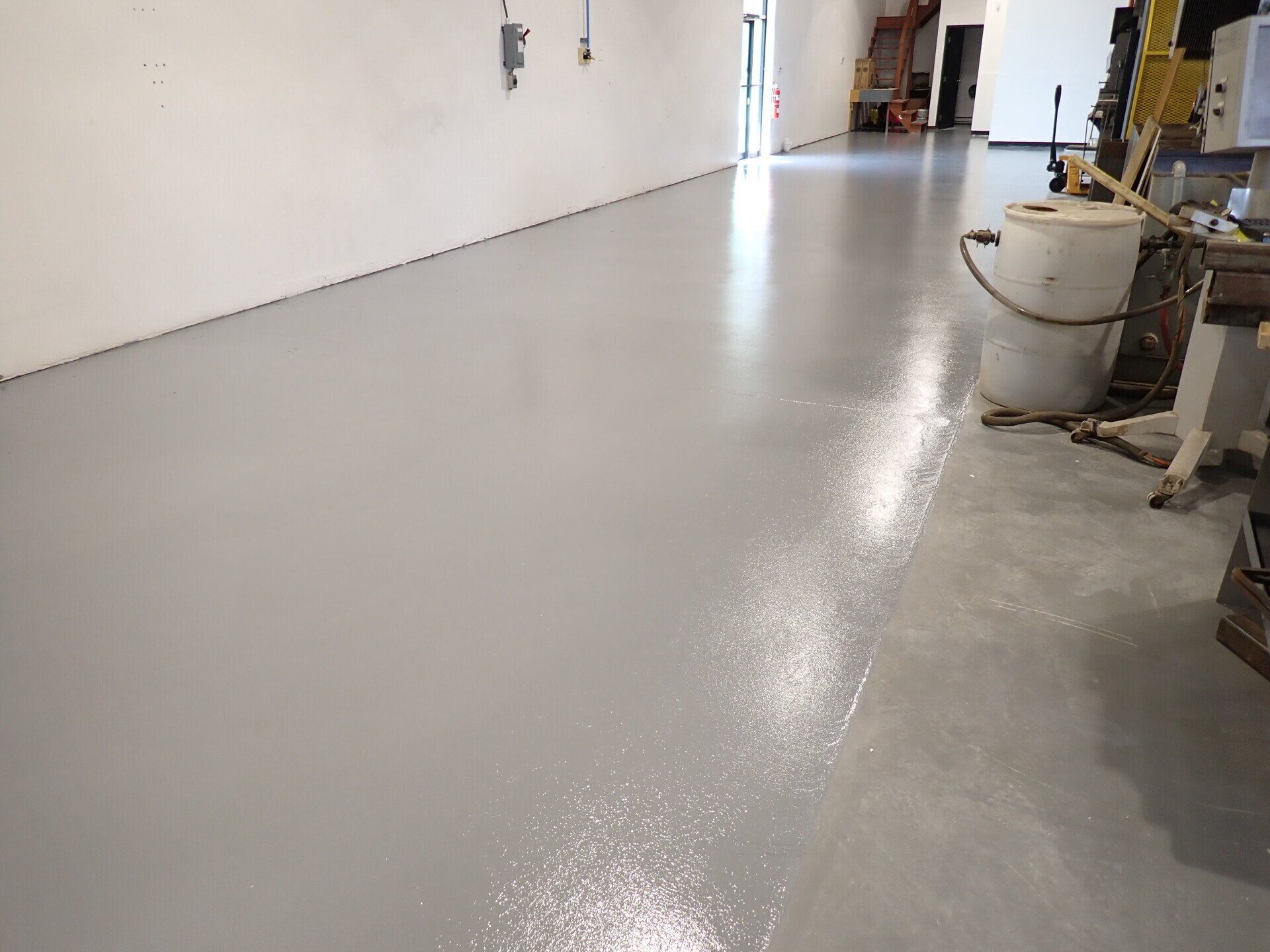 Une grande pièce avec un sol gris et des murs blancs.