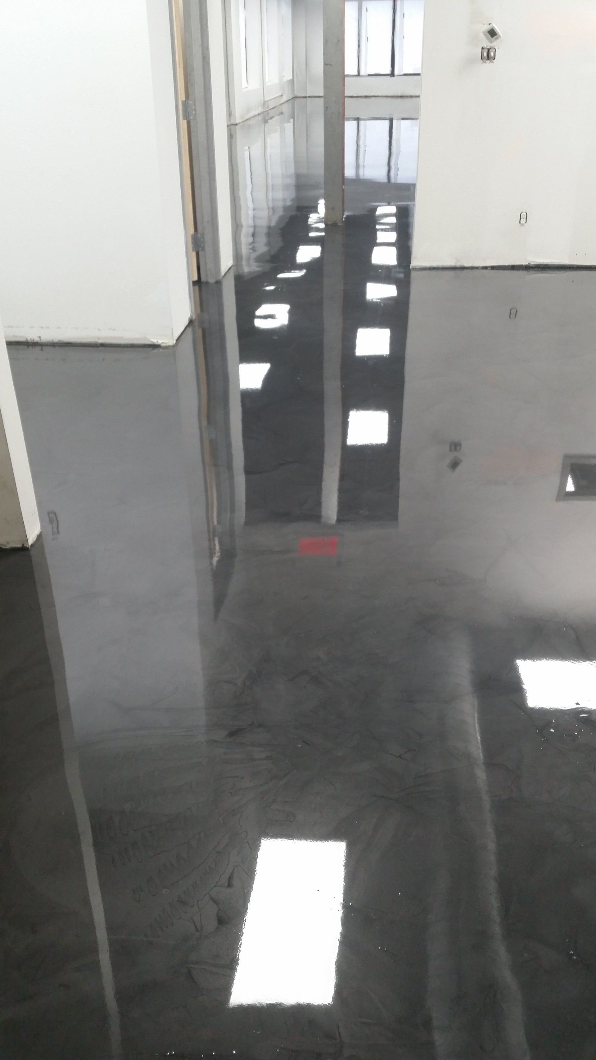 Un couloir avec un sol noir et des murs blancs