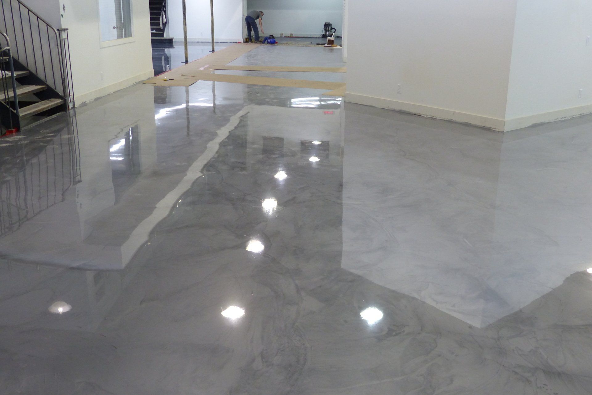 Une grande pièce avec un sol en béton brillant et des escaliers.
