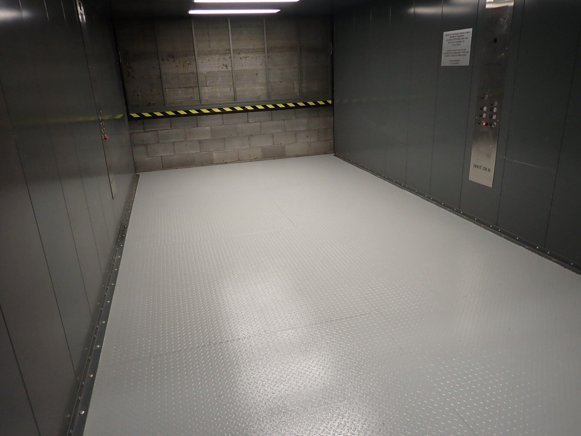 Une pièce avec un sol blanc et un mur noir.