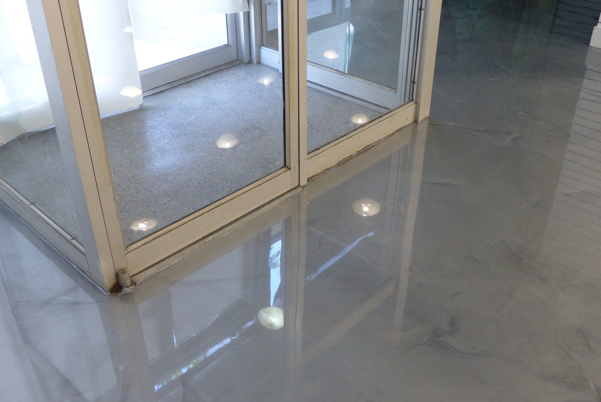 Une porte coulissante en verre dans une pièce avec un sol en marbre.