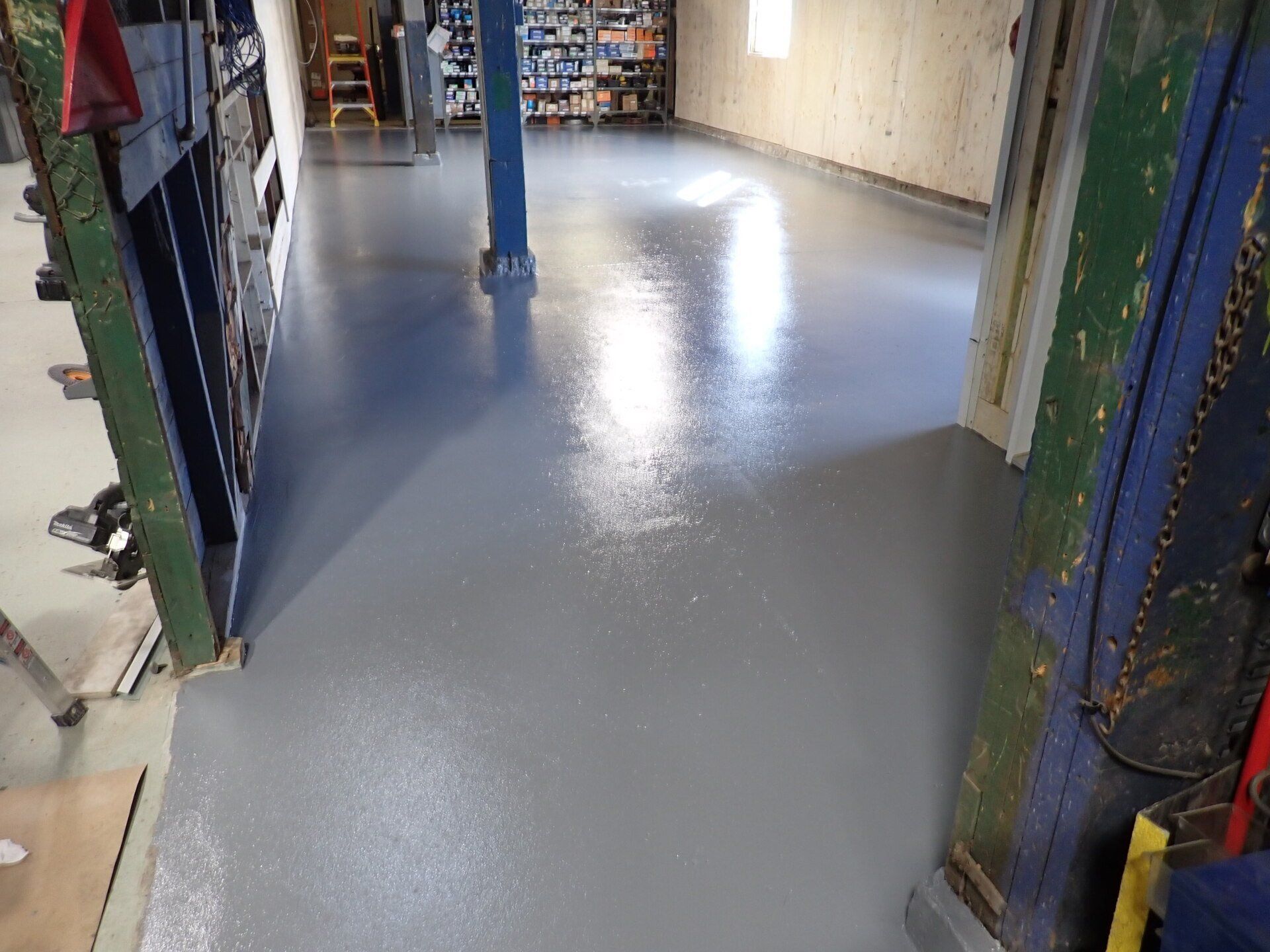 Une pièce avec un sol gris et un poteau bleu au milieu.