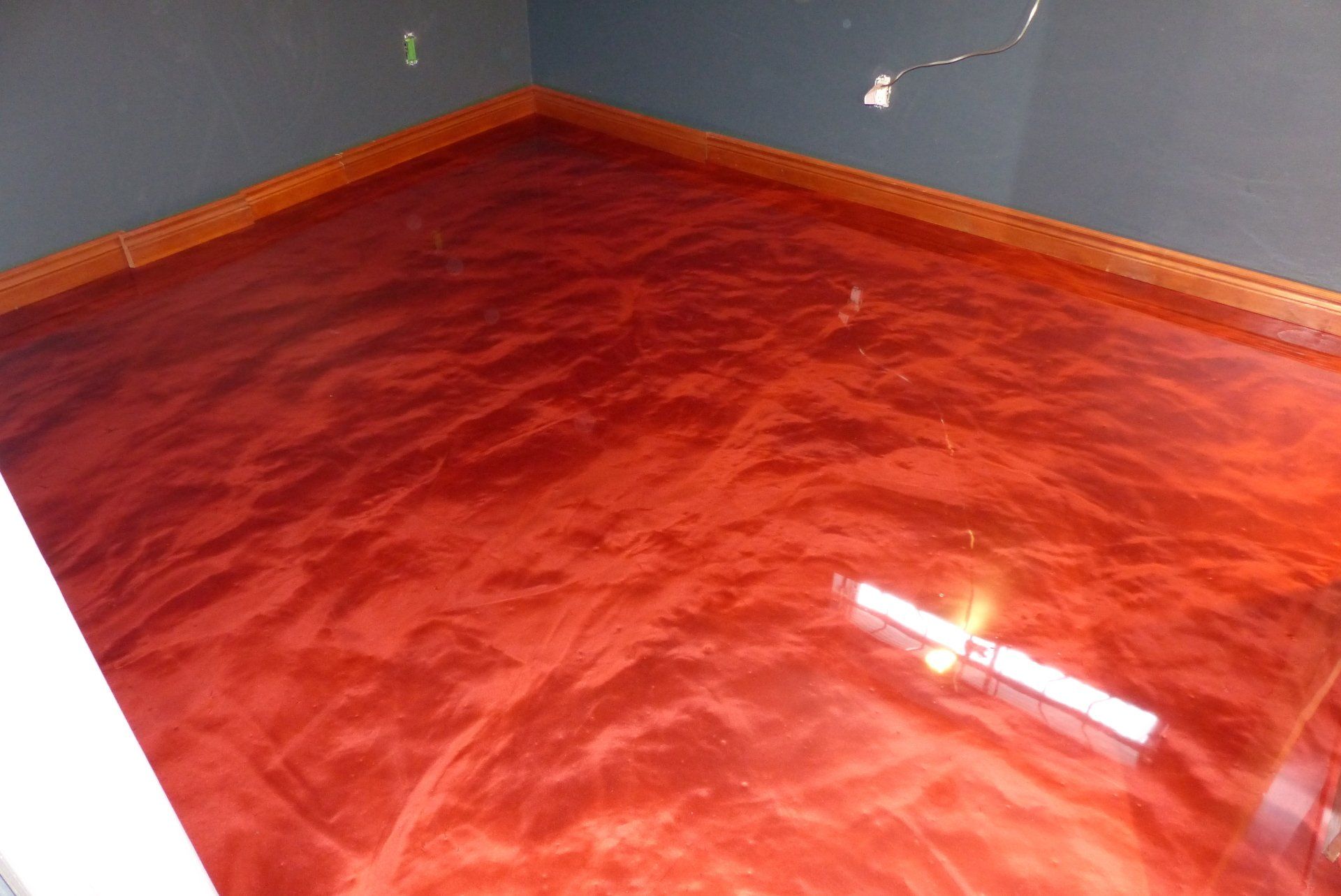 Un sol métallique rouge dans une pièce avec un mur gris