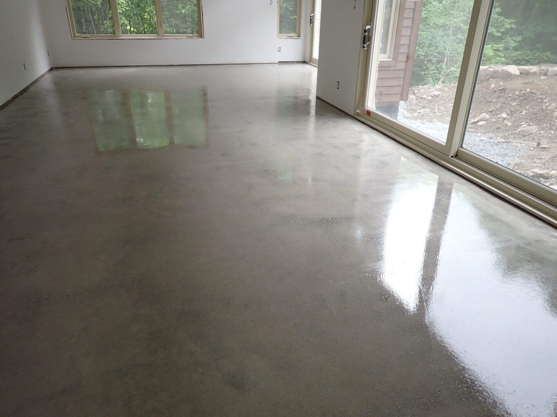 Un sol en béton brillant dans une pièce avec une porte coulissante en verre