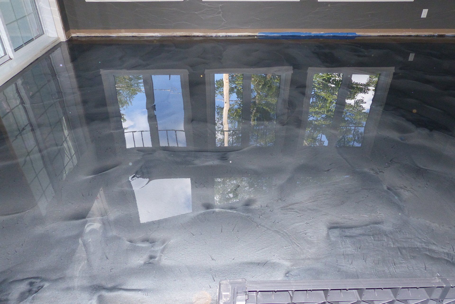 Une pièce avec un sol métallique brillant et un reflet de fenêtres.