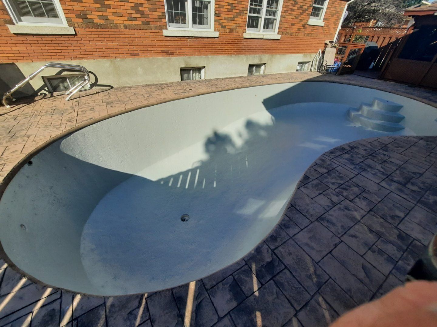 Une personne se tient à côté d'une piscine avec un bâtiment en briques en arrière-plan.