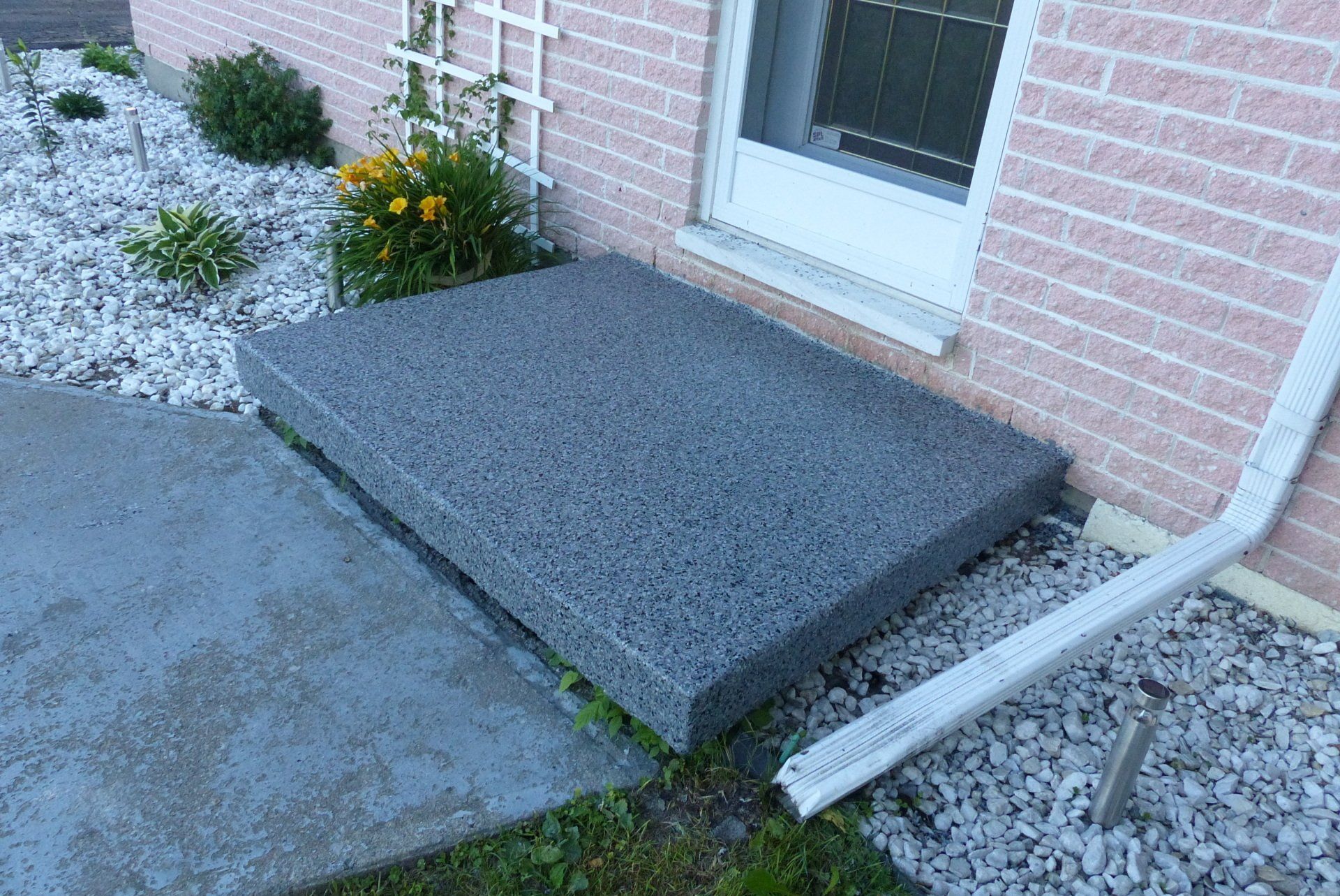 Une maison en brique avec une marche en béton devant elle.