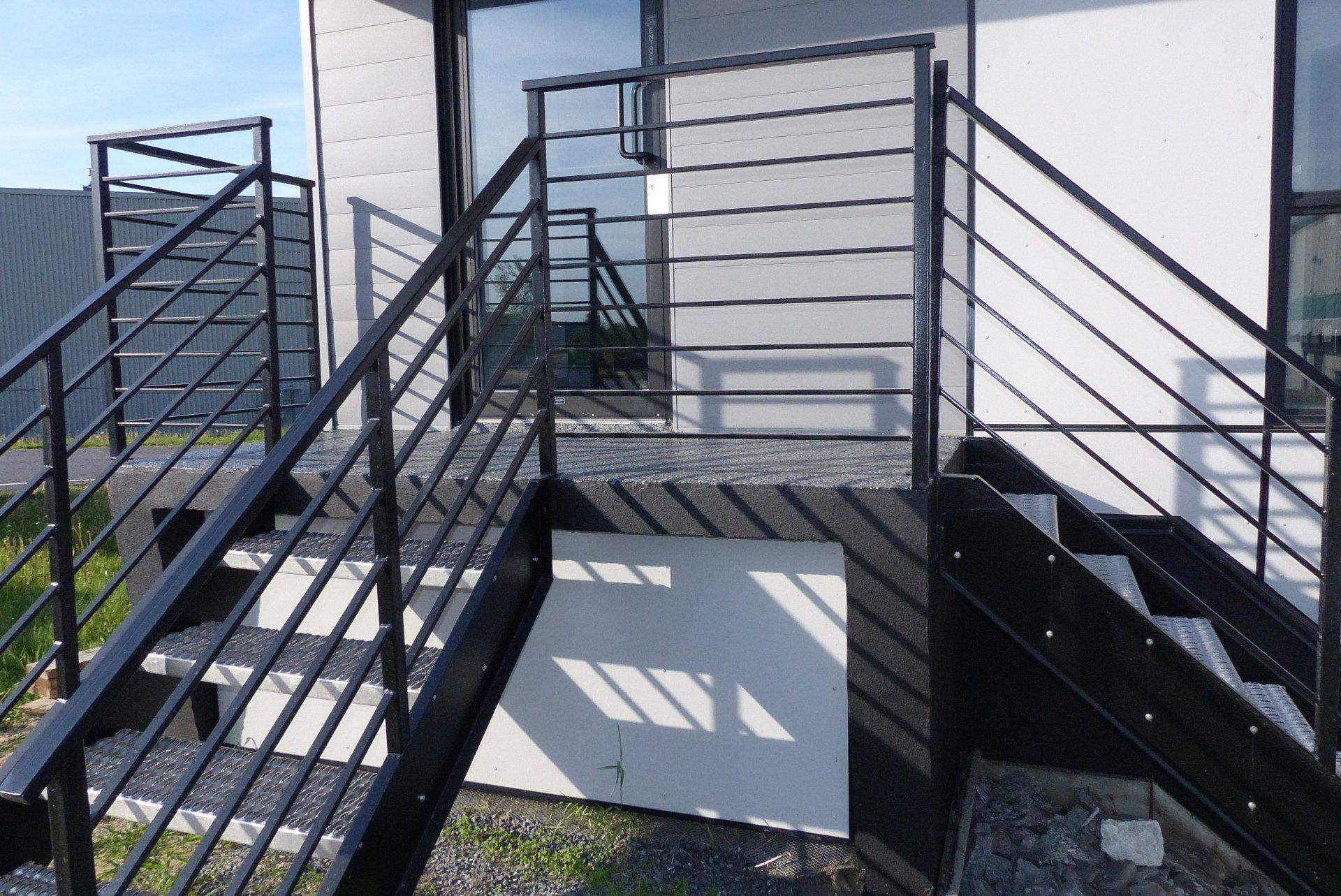 Un ensemble d'escaliers menant à un bâtiment avec une rampe en métal.