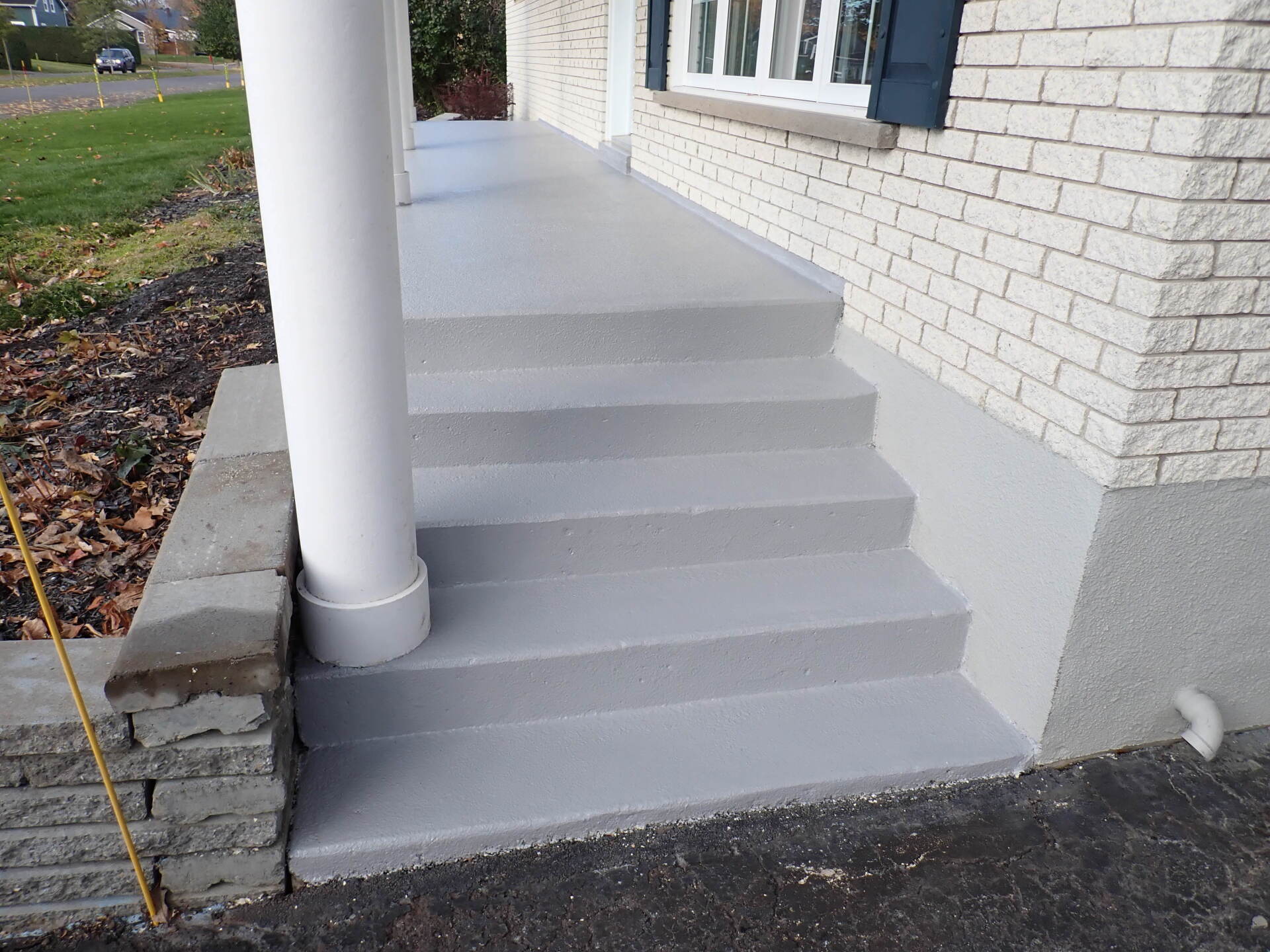 Une maison en briques blanches avec un porche et des escaliers