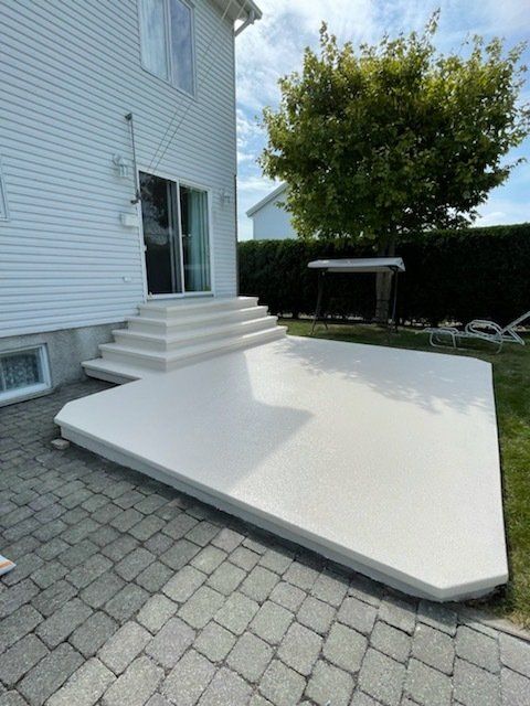 Un patio blanc avec des escaliers et une maison blanche en arrière-plan.