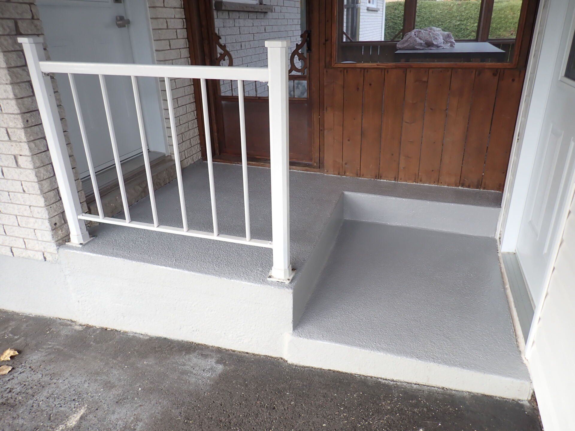 Un porche avec une balustrade blanche et des marches menant à une porte.