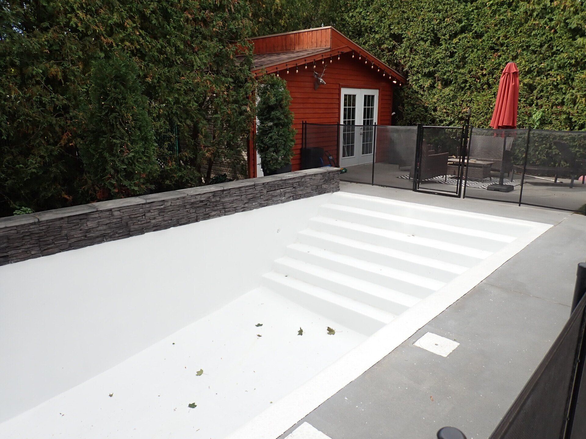 Une piscine avec une maison rouge en arrière-plan