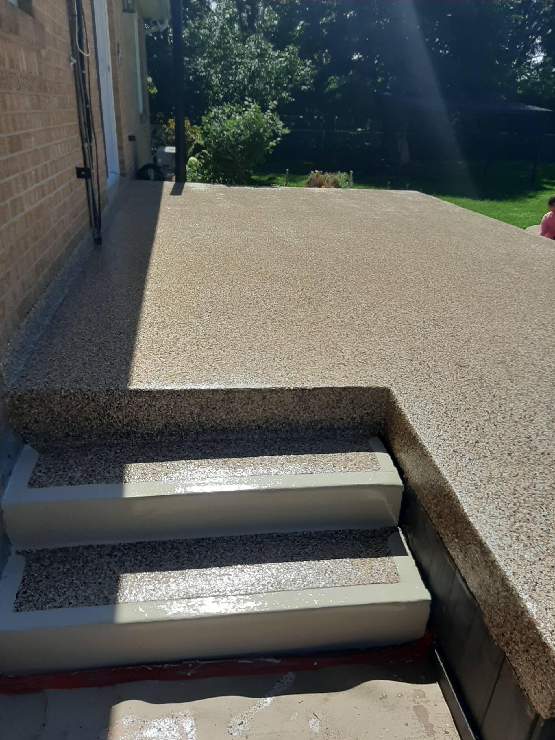 Une terrasse avec des escaliers qui y mènent et un bâtiment en briques en arrière-plan.