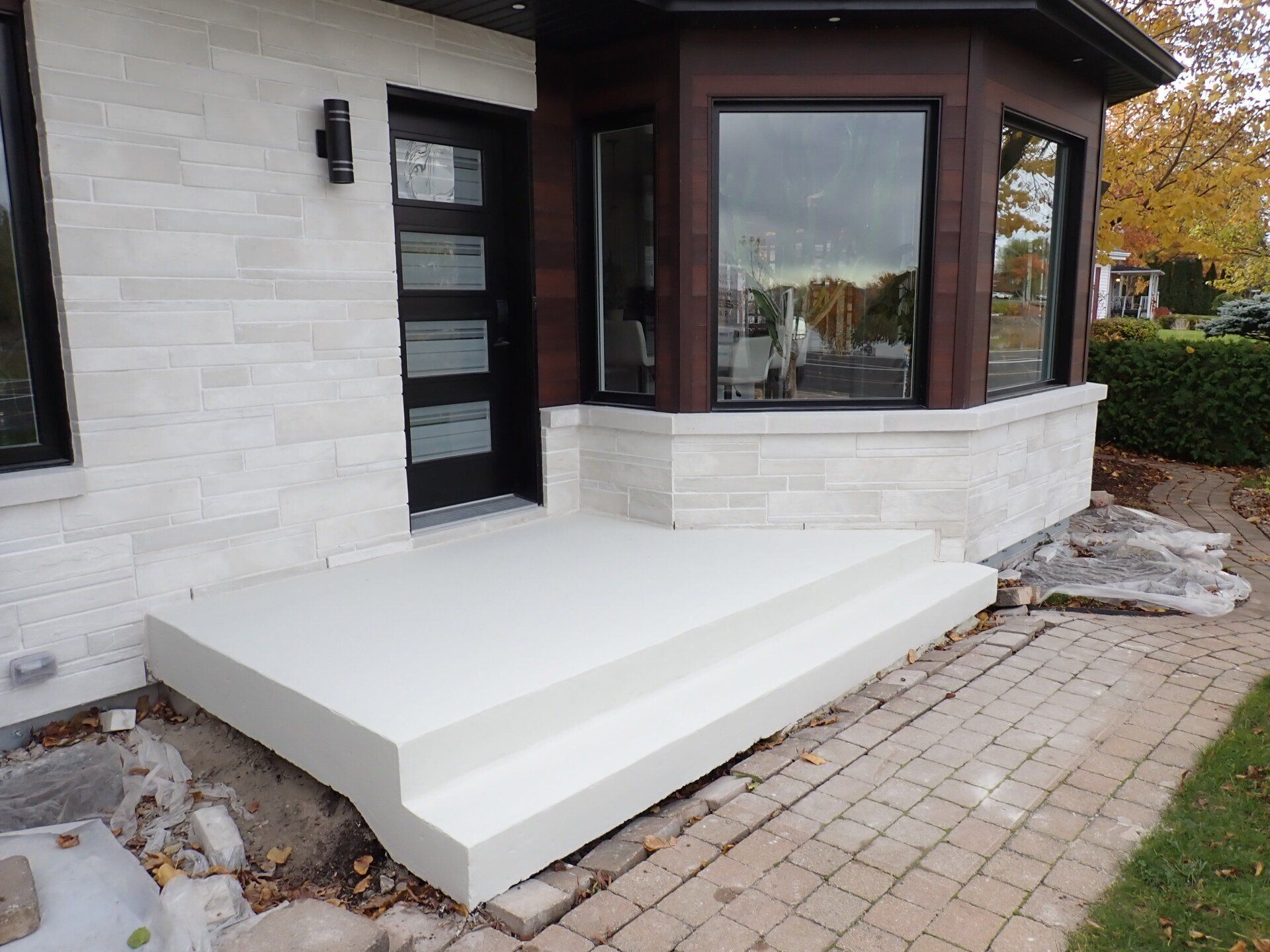 Un porche blanc avec des marches menant à la porte d'entrée d'une maison.