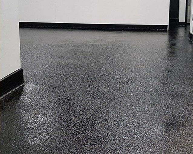 Un sol noir dans une pièce aux murs blancs.