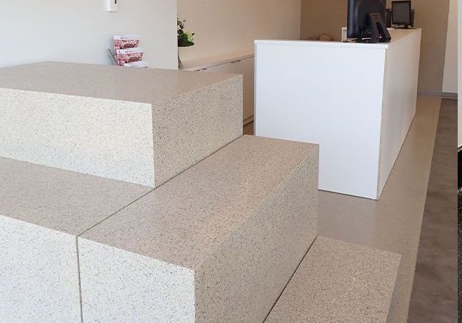 Des blocs de béton disposés en escalier mènent à un comptoir blanc. Aménagement intérieur, palette de couleurs neutres.