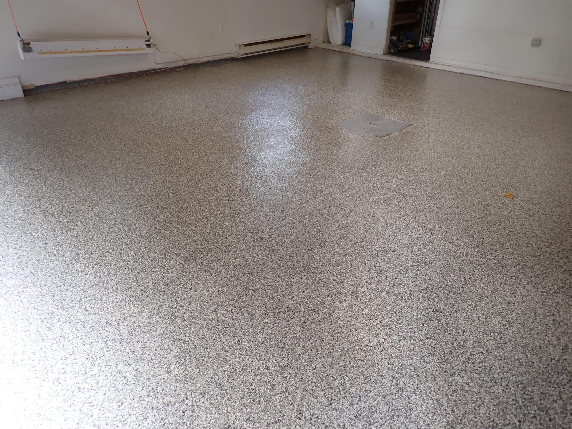 Une pièce avec un sol en béton et un mur blanc.