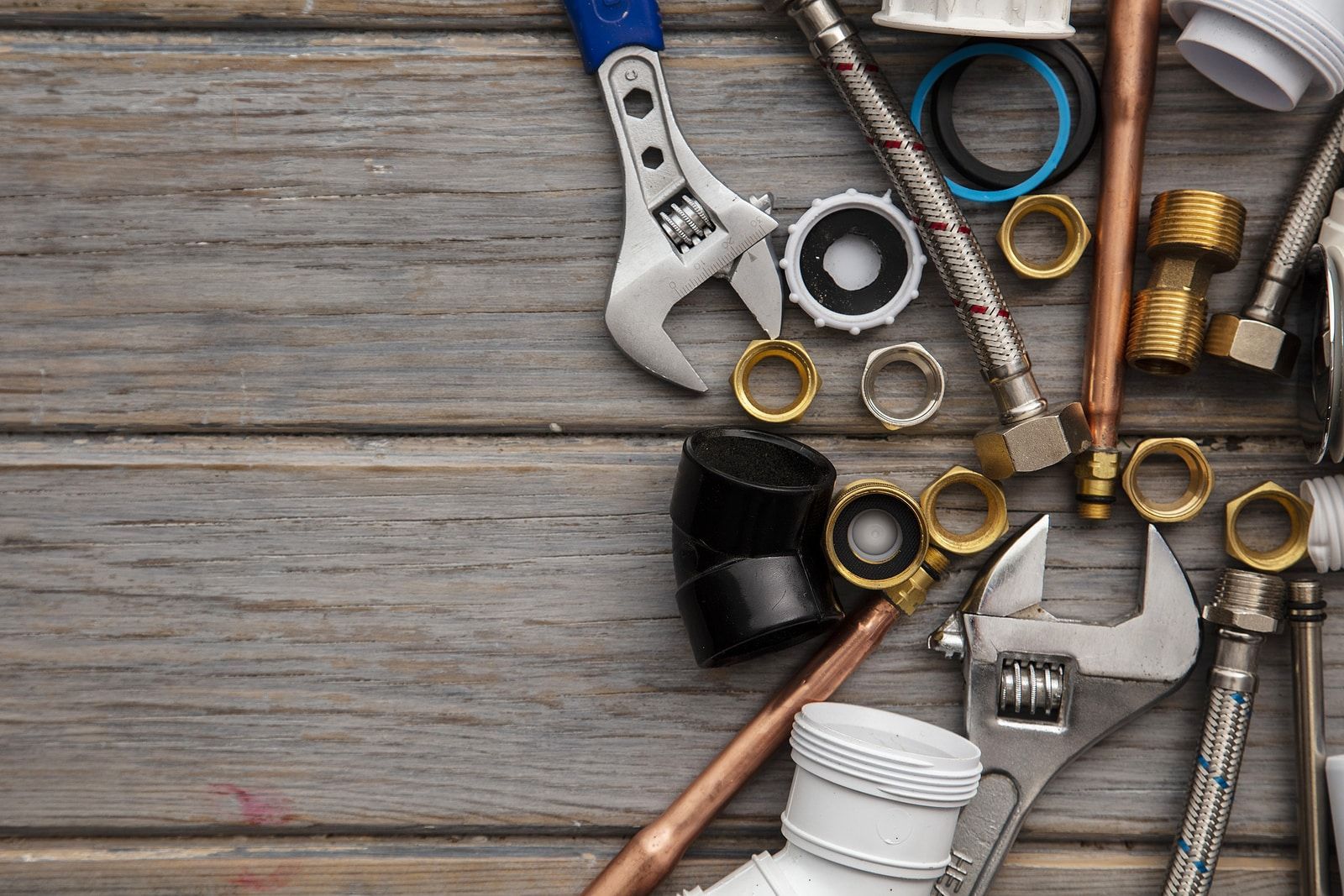 A bunch of plumbing tools are on a wooden table.