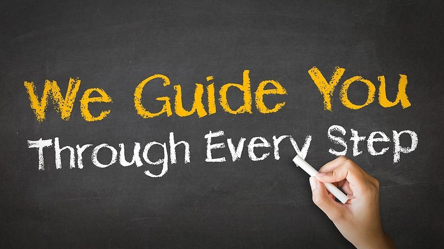 A person is writing on a blackboard that says we guide you through every step