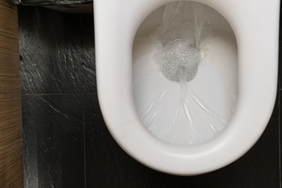 A close up of a toilet with water running out of it.