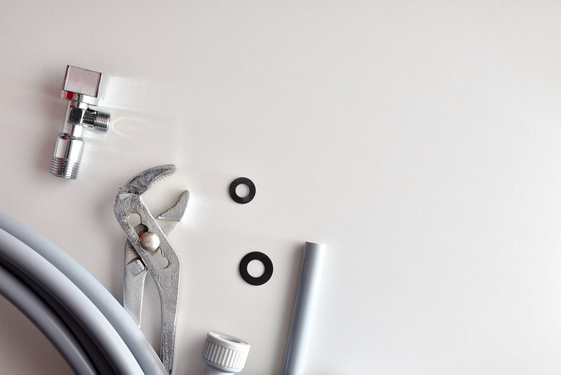 A pair of pliers is sitting next to a hose on a white surface.