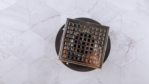 A drain cover is sitting on top of a marble tile floor.