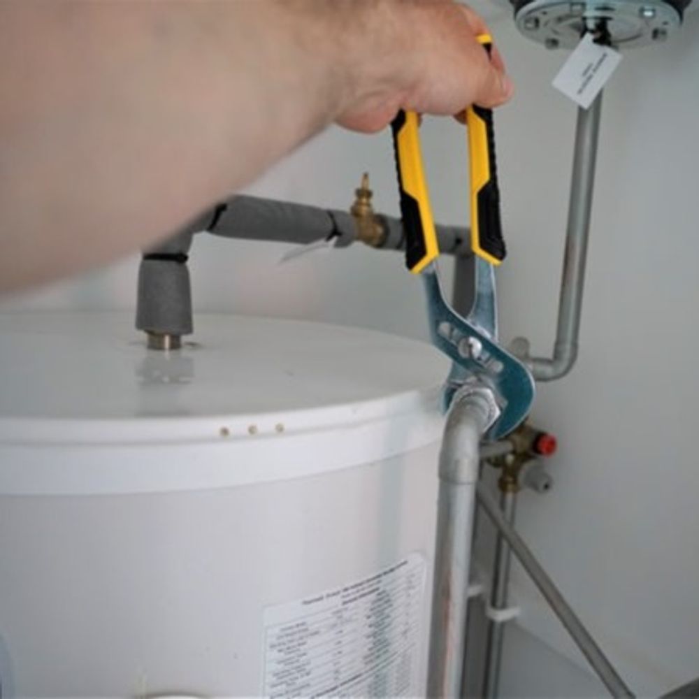 A person is fixing a water heater with a wrench