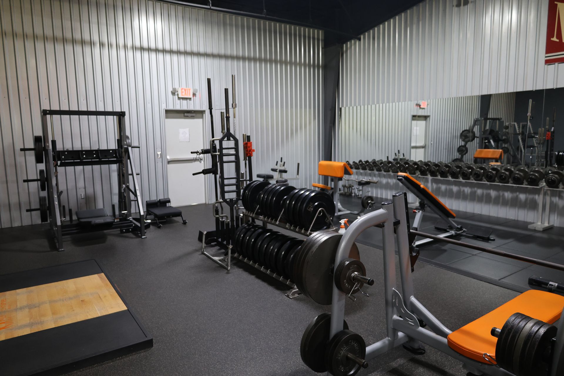 A gym filled with lots of exercise equipment and a large mirror.