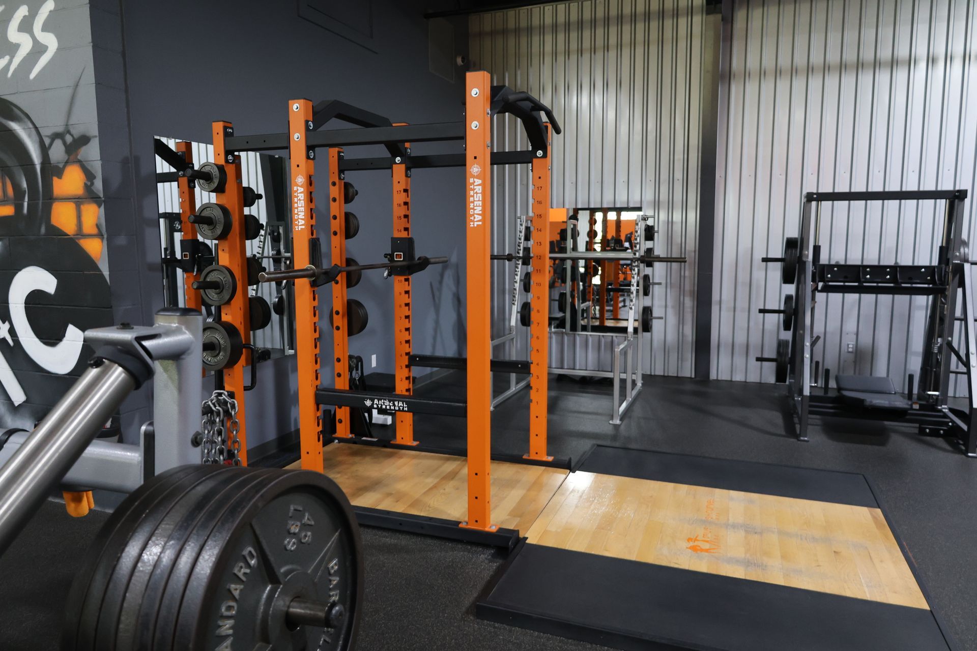 A gym with a lot of equipment including a squat rack