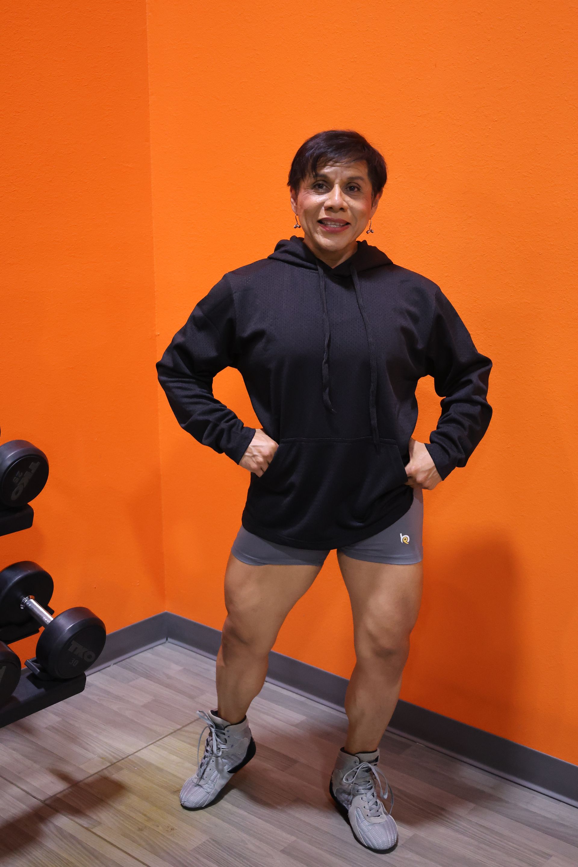A woman is standing in a gym with her hands on her hips.