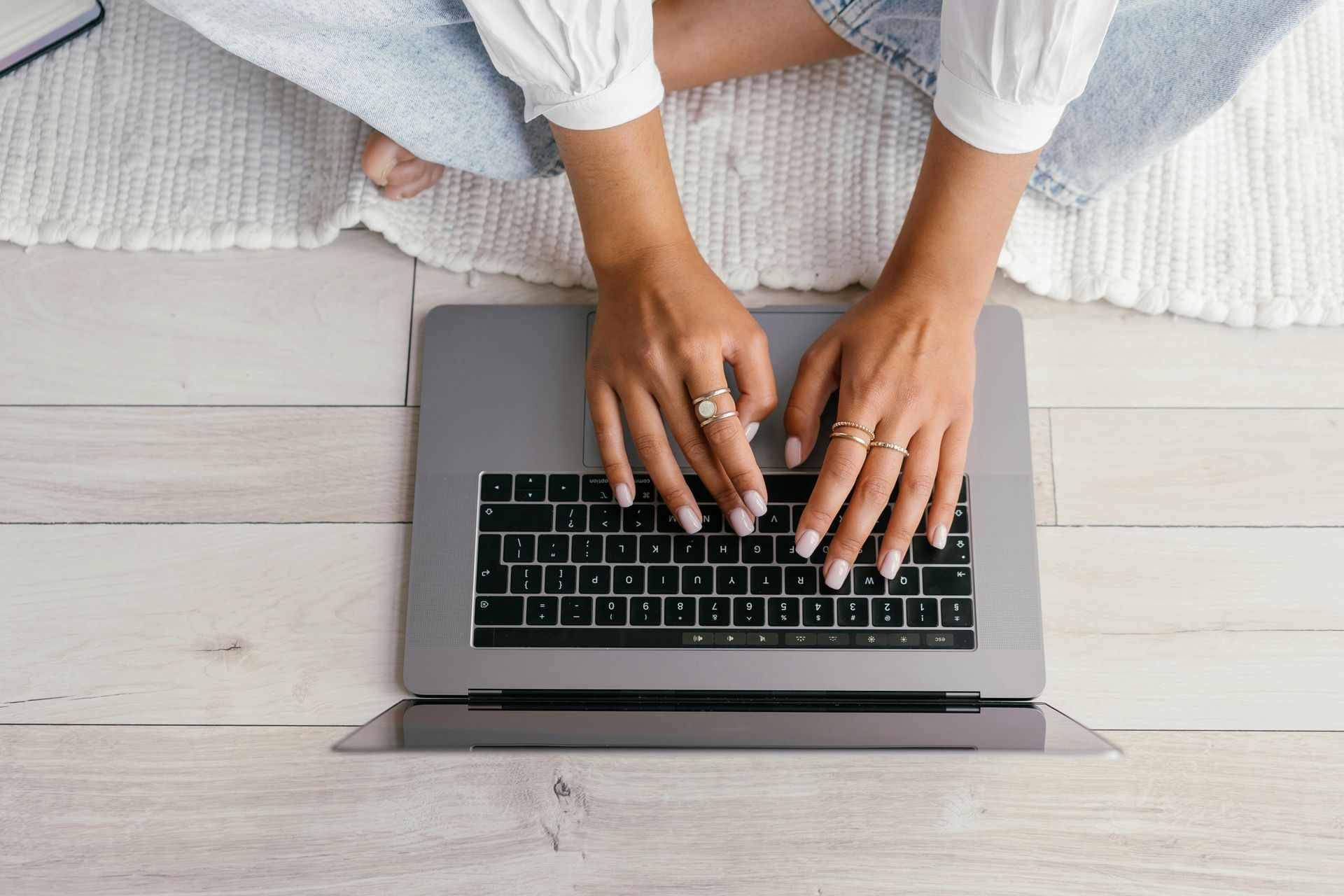 A woman is sitting on the floor using a laptop computer.