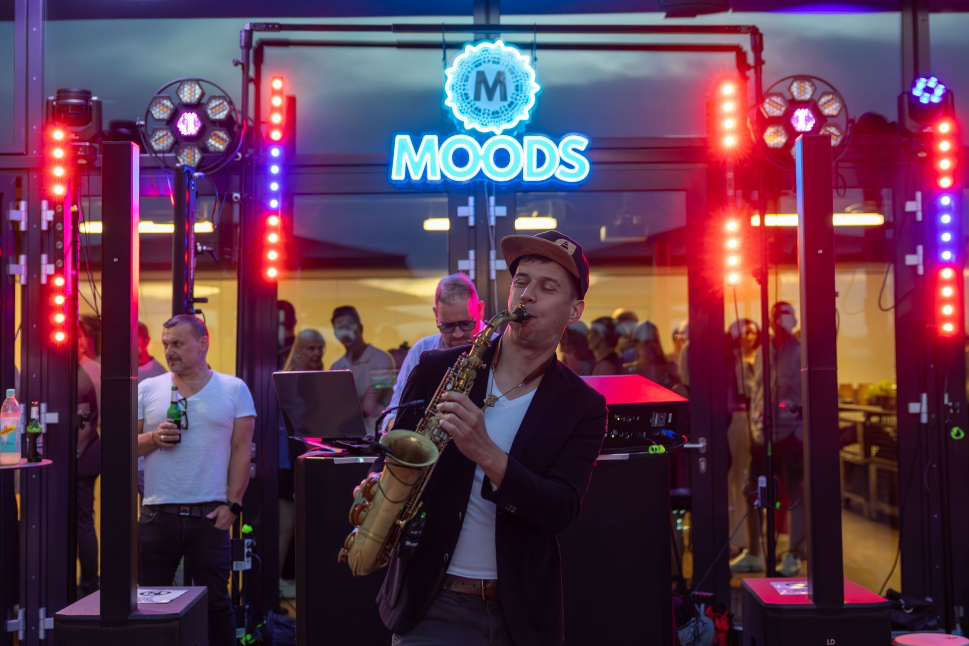 Ein Mann spielt Saxophon vor einem Schild mit der Aufschrift „Moods“.