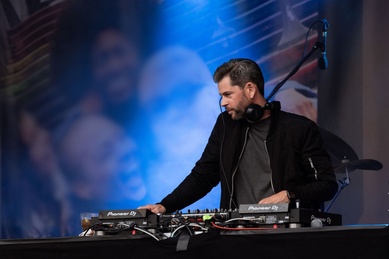 Ein Mann mit Kopfhörern spielt auf einer Bühne ein DJ-Set.