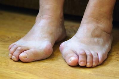A close up of a person 's feet on a wooden floor.