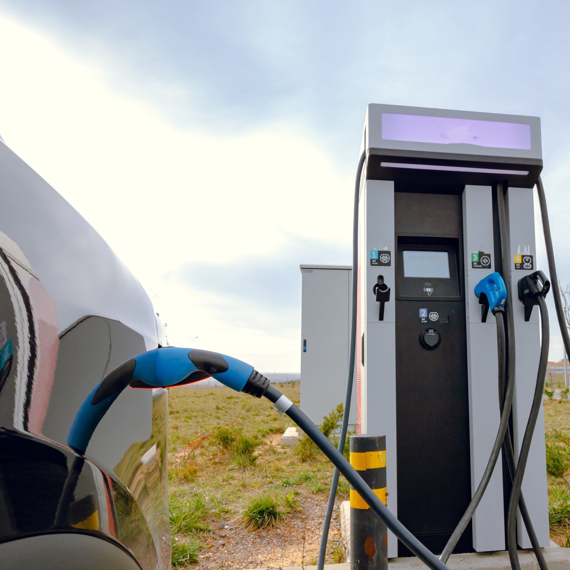 An electric car plugged into a charging station, with the charging cable connected to the vehicle.