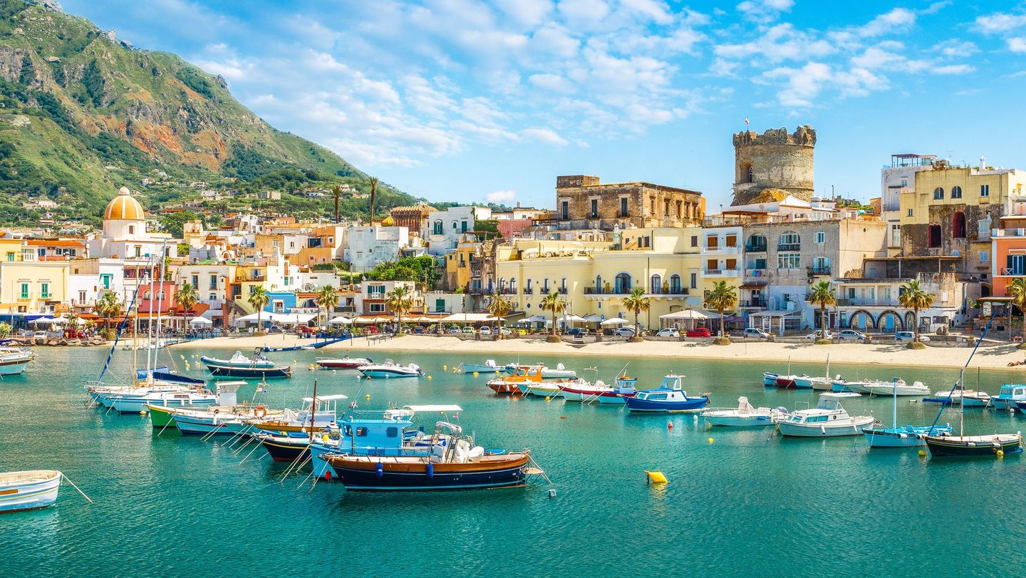 Sunny Ischia harbor with colorful boats and seaside houses, ideal for Italy tours.