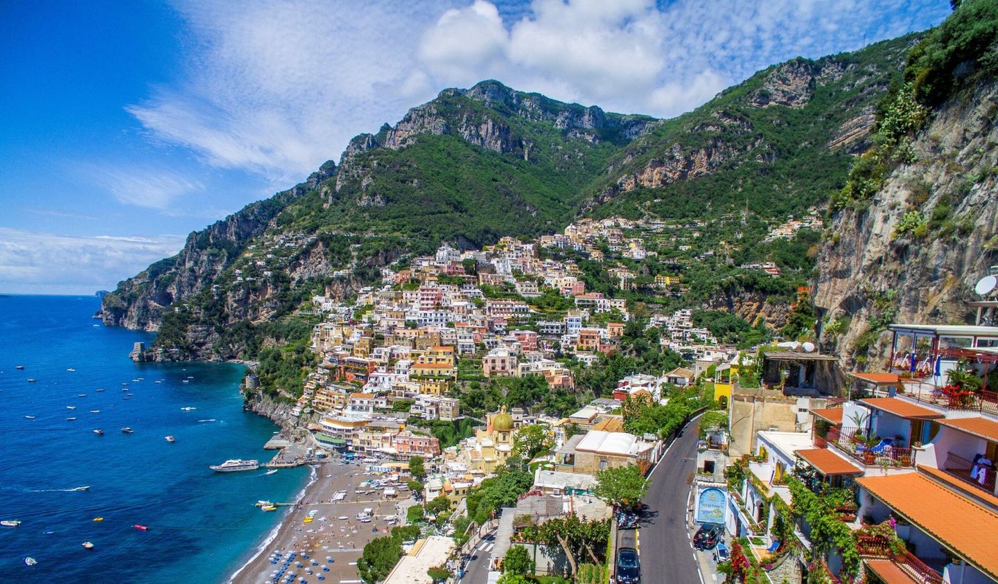Positano's cliffside landscape with colorful buildings, clear blue sea, and beach ideal for tour experiences.